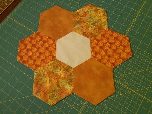 Use the seams of the pumpkins to evenly align the brown hexagon over the raw edges of the hexagon circle.