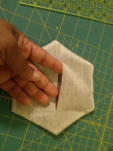 Trim away the excess fabric and fusible web around the outside of the hexagon, leaving 1/8 to 1/4" seam allowance on all sides.