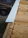 On the long horizontal eaves (on top of the gutterboards) the drip edge goes on top of the OSB sheathing over the gutterboard and under the tar paper.