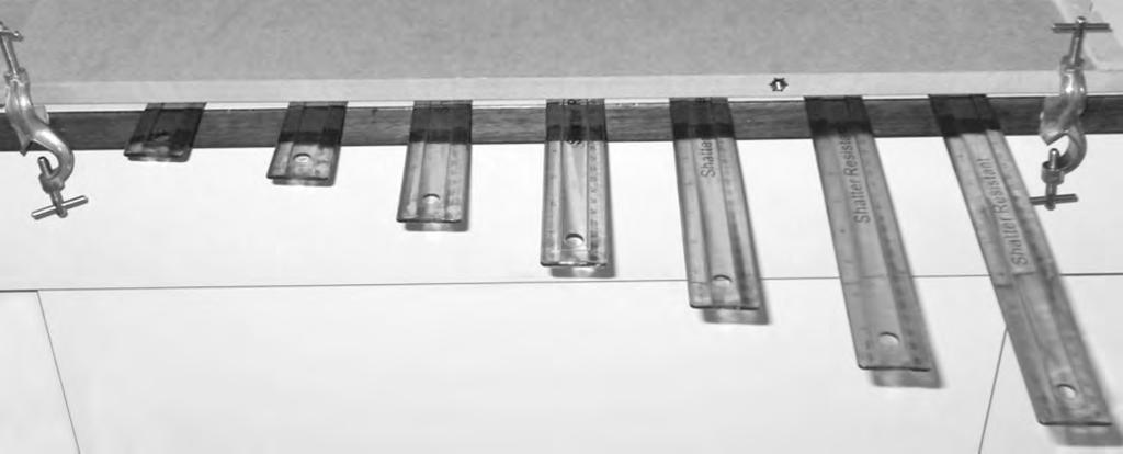4 A student makes the ruler piano shown in the photograph. One end of each ruler is held flat on the desk whilst the other end is set into oscillation.