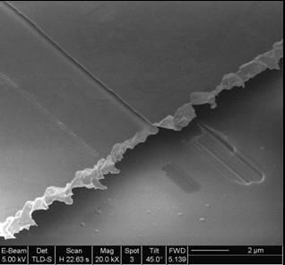 Figure 5.17. SEM images of FIB milled gap across a suspended center conductor section (left) and close up of the angled cut (right). 5.3.