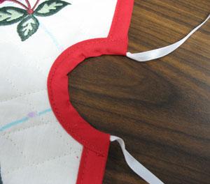 Tie a knot at one end of the ribbon and then tuck about 1 inch of the other end in between the bias tape on the inner ends of the tape. Pin in place.