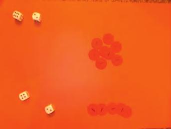 Player 2 rolls two dice and collects the amount shown in place value counters. Each time the total of 10 or more is reached, the player exchanges them for a 10 counter.