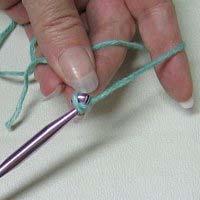 around the crochet hook. Pull the hooked yarn through the loop that is the slip knot.