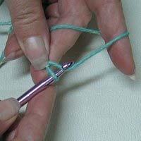 Holding the 'tail' of the slip knot with your thumb and finger, hook the yarn from behind