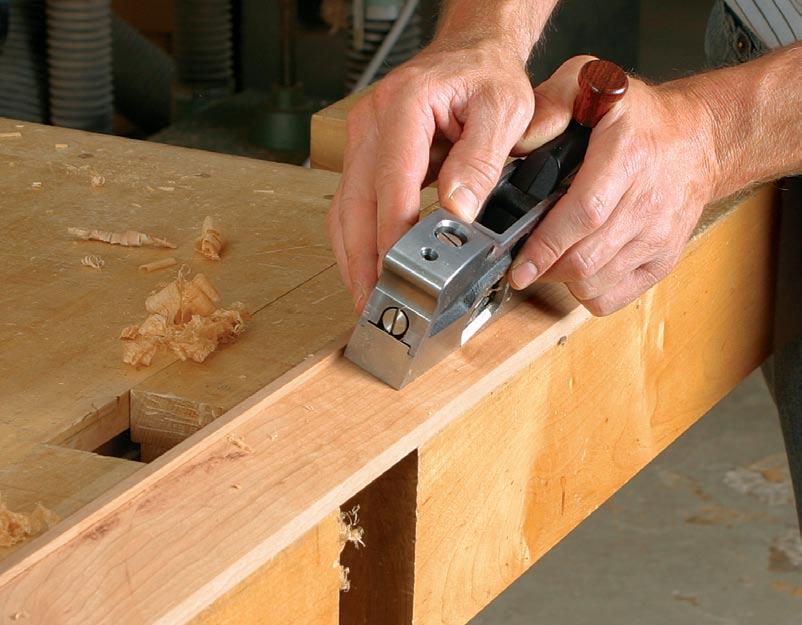 Hold a small board in one hand and plane with the other. On a larger board, plane with both hands, securing the board to the workbench with bench dogs and the tail vise.