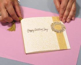 Tie a decorative gold cord tassel around the fold to complete the card.