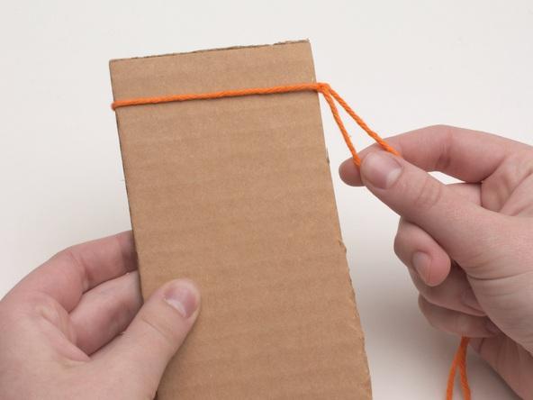 This forms a loop that will serve as the holding cord to which you will tie the knotting cords. Make sure the ends of the cord are equal in length; they will be used later to form the strap.