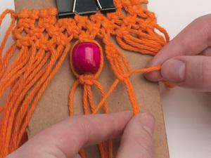 On each side of the center bead, tie a sennit of half knots to form a spiral pattern, using 4 cords for each side.