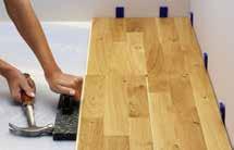 Cut the board where you marked. Angle it into place and tap it in with the pull bar. Place a spacer between the short end and the wall.
