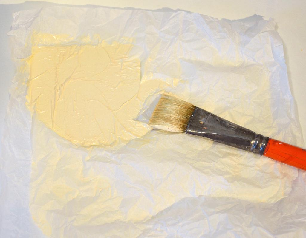 Trim any excess tissue paper that s extending off of the canvas using scissors or a cutting knife.