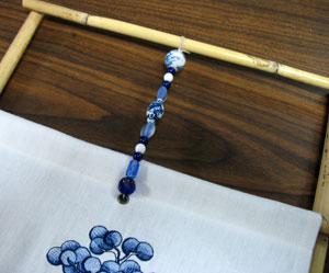 Pull the cord taut. Add the beads to the front side, and tie and knot the other end of the cord onto the top bamboo piece.