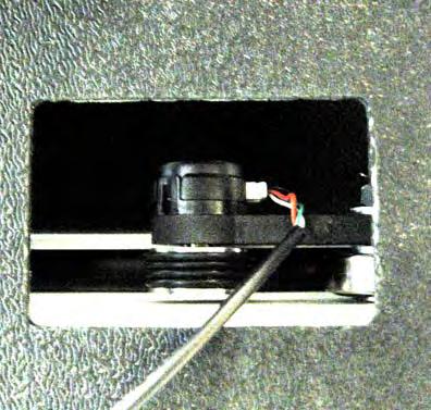 The lower carriage encoder with the encoder wire connected is pictured. The ridged wheel of the encoder is seated on the black track of the frame.