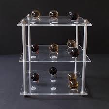 Visualizing the board: This is a photo of a 3D tic-tac-toe game made from 4 long bolts, 4 rounded top thumb bolts, three acrylic trays, 14 amber colored marbles and 14 green colored marbles.