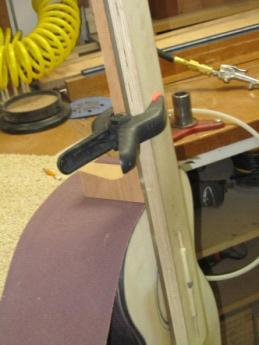 Sanding action: the paper is pulled down and to the right while the jig is allowed to rest on the guitar body.
