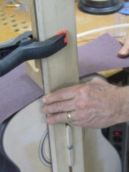 The upright portion of the jig is then lifted with the left hand, allowing the right hand to feed the sand paper back under the jig to prepare for another pass.