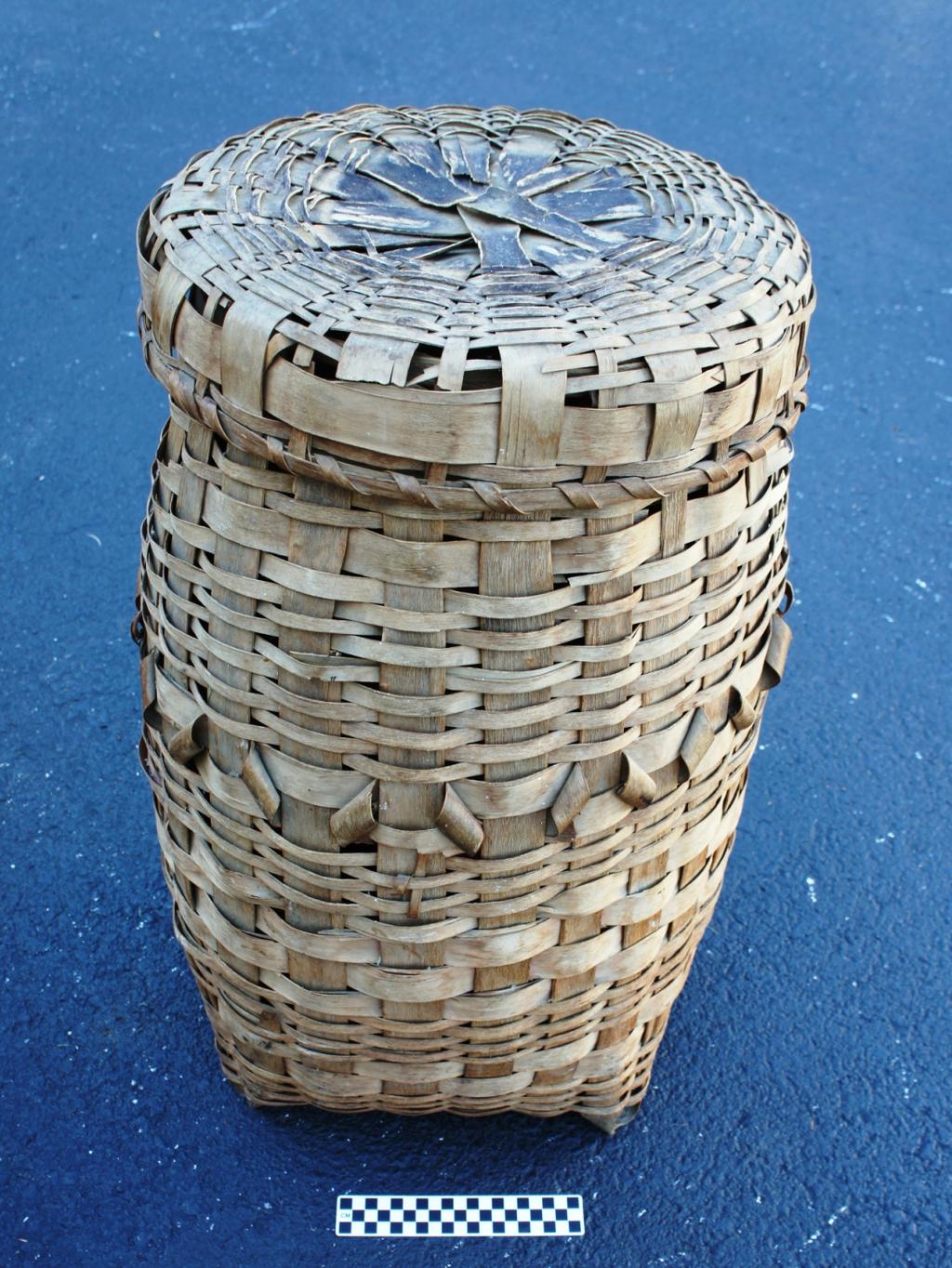 The last large decorated example in the Wôbanakik Heritage Center collections is a more or less cylindrical basket with a square plaited bottom.