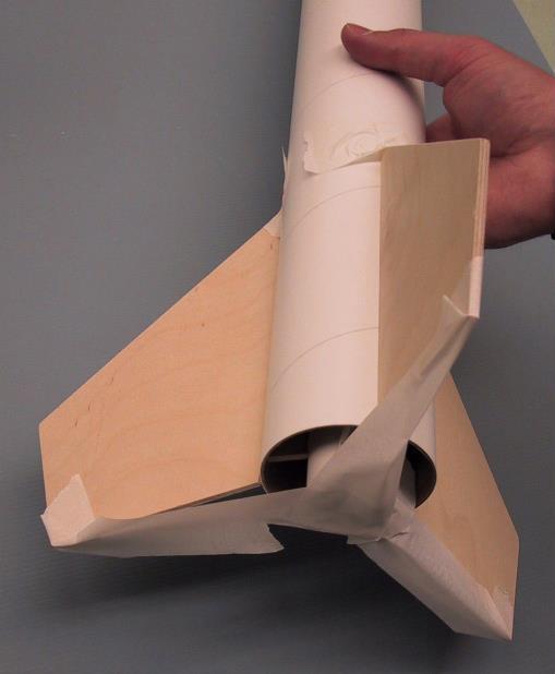 Hold the fin against the motor tube and align the fin as straight as possible. Tape the fin in place to hold it straight while the glue sets. 6) Repeat for each of the three fins.