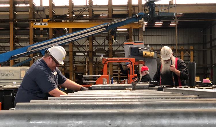 A crew works on a recent install of a material handling system from HE&M. for customers with miter sawing operations.