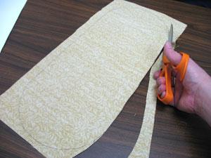 To prepare the fabric for the bottom of the clutch. Cut two pieces of the print canvas by pinning the pattern piece in place, tracing it, and cutting out the shapes.