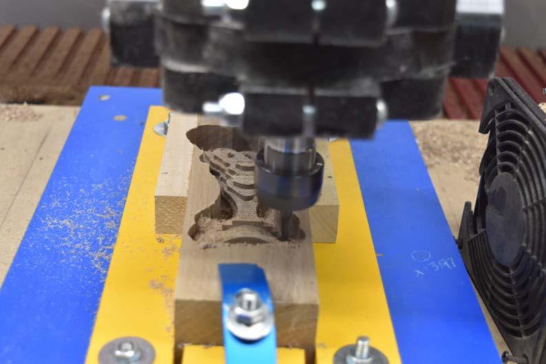 For this part you have to glue on two outriggers, this is to support the head in the finish machining. Vacuum the top of the fixture. Install the 1/16 tapered ball nose bit.