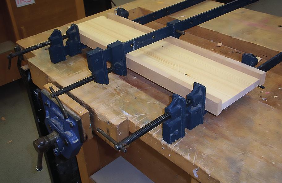 1. (continued) (b) The board for the upright and base was made by gluing strips of wood, edge to edge as shown in the picture below.