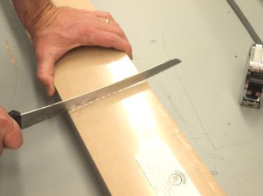 Then, using your bread knife, score the hardboard packaging, cut the shrink-wrap on all