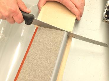 Remove the hardboard. Using the bread knife, make a straight, square cut through the foam.