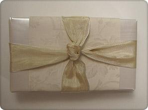Centering the ribbon on the bottom of the box, bring the both sides of the ribbon to the center top of the box and tie in a knot. 7.