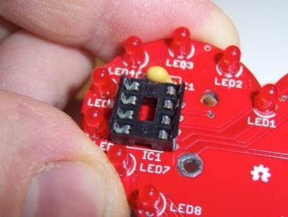 There are two ways that it will fit either will work. The button should stay in the board when you flip it over to solder. Solder it in, and clip the leads.