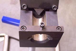 This is accomplished by having a pointed SLIDING PUNCH entering the end of the tube at an angle to the DIE PLATE.