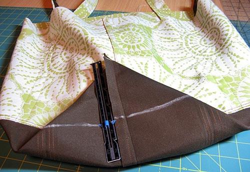 22. As you pull, the fabric will begin to make a little peak with the corner point at the top and the seam line running down the middle of one side. 23. Center the side seam within this triangle peak.