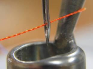 d. Take the thread through the front pigtail thread guide as you did in the step above, then through the needle, front to back. Make sure the needle is inserted correctly.