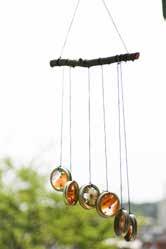 Push the cutouts into the canning jar lids to make suncatcher. Tie around the lids and tie the other end to a stick. Hang on the porch or patio to see!