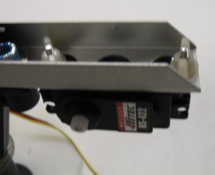 step. Place the servo underneath the 6-hole bracket with the white drive gear
