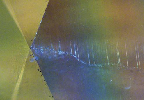 Figure 6. The conventional microscopic image of a brownish-greenish yellow HPHT-treated type I diamond on the left shows a crack surrounded by polish lines.