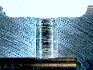 Figure 15. Exit burr for a hole drilled with 5.8 mm dia. drill. The pinch of the feed mark equal to the feed per revolution (0.13mm) serves as a geed scale.