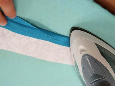 Press the seam. Fold the raw edge of the solid colored fabric over 1/2" to the wrong side and press.