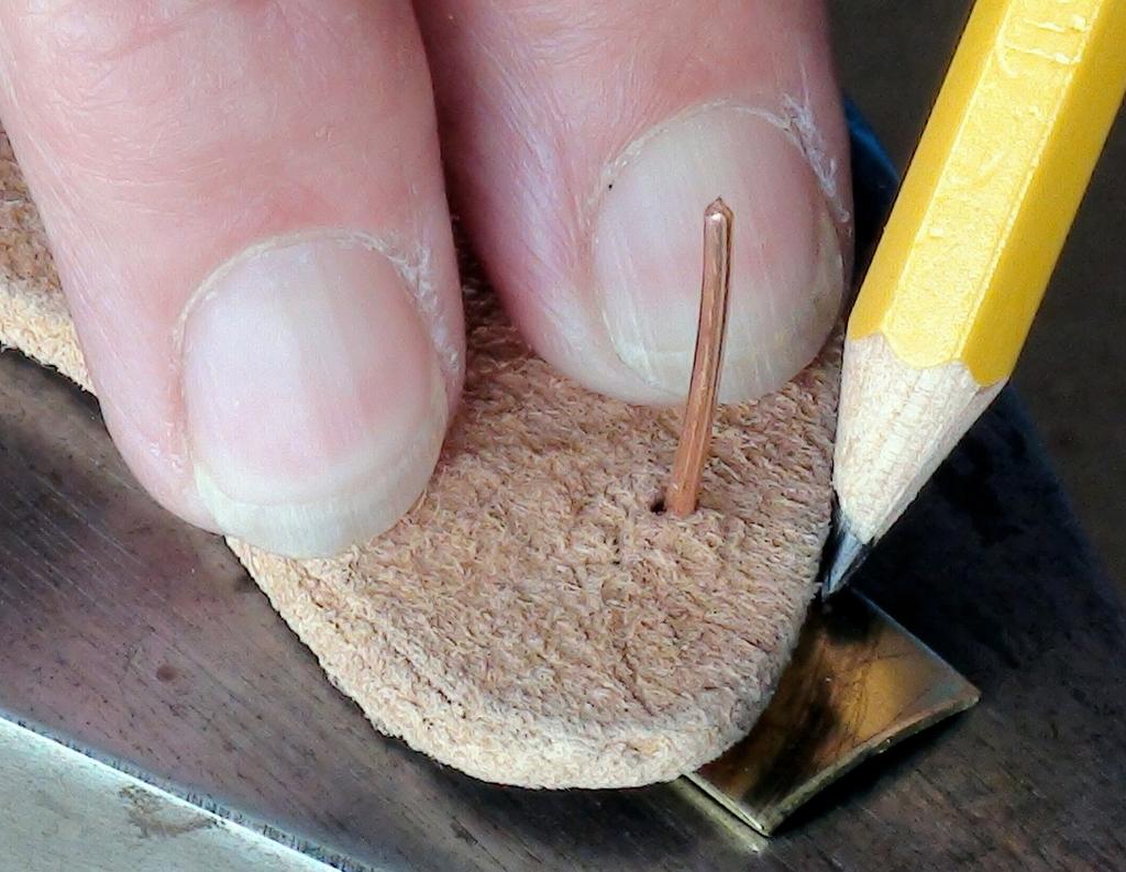 Once the awl has punctured the back of the leather, use the awl to work from both sides of the leather in turn to enlarge each hole. Set the leather aside. Prepare the brass strip.