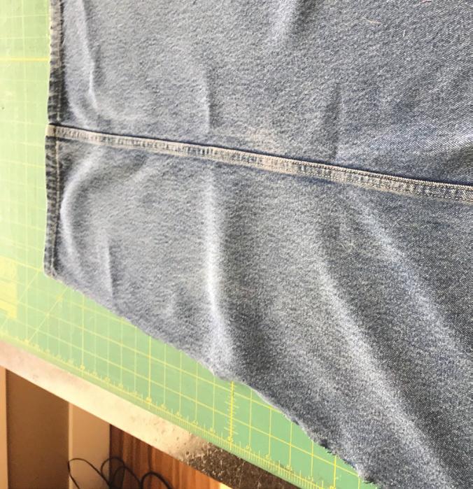 Use the finished hem of the jeans as the top of the apron.