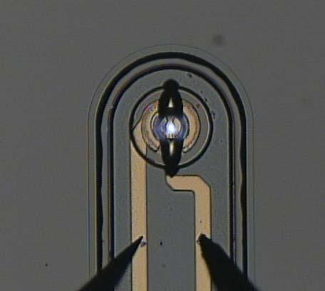 The VCSEL is located at the center of the chip and is shown emitting light in the close-up view of Figure 11(b). Surrounding the VCSEL is a 1.5-mm-diameter RCPD.