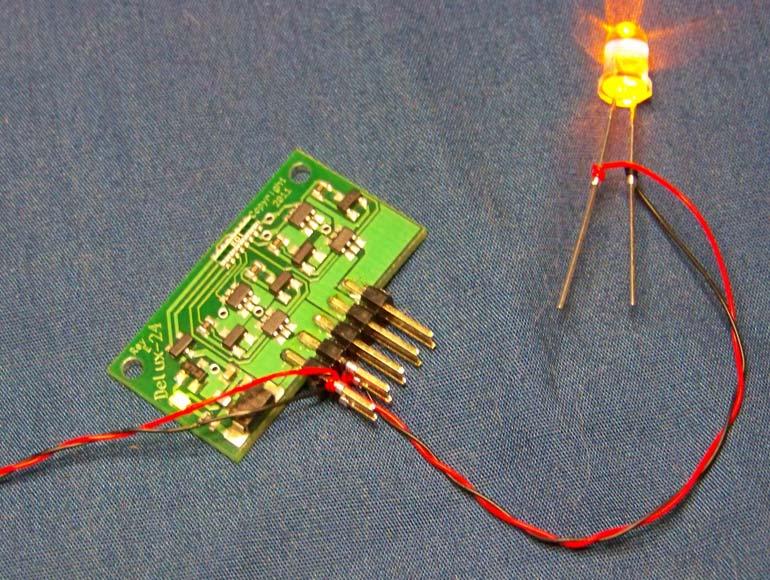 The following pictures show how to hook up wire-wrap wire to the Delux-Flasher 24 board. Hookup for one LED, showing the red and black wires for power and the LED. One LED hooked to the Delux-24.