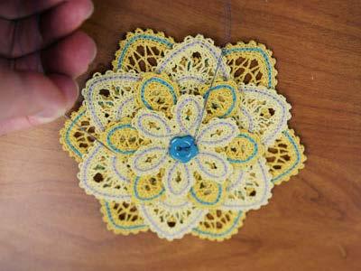 Using a needle and thread, sew a button in the center of the flower to tack all the layers together.