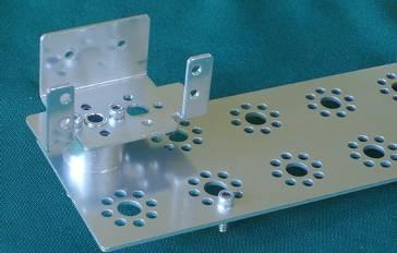Place the bottom of the spacer and the two screws into the far back left set of holes in the plate, as shown.