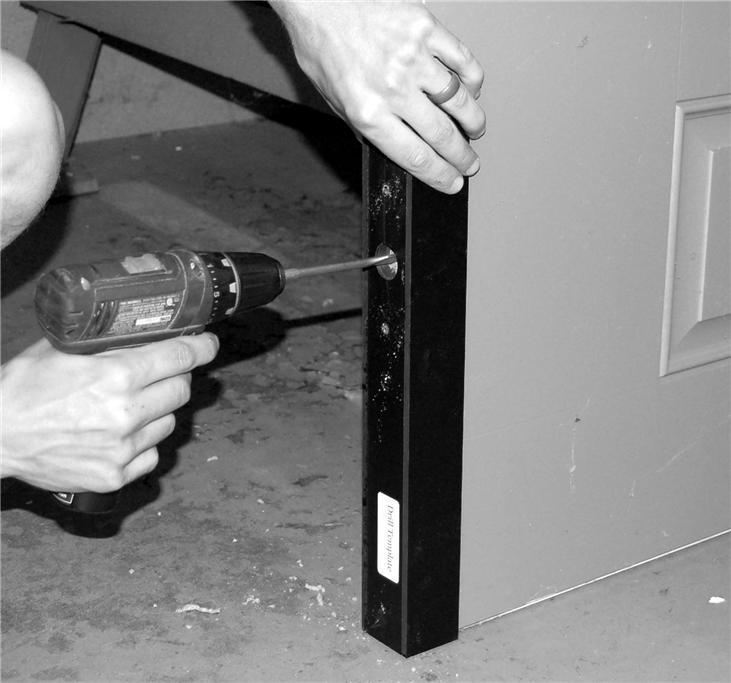 Step 18: Place hole template guide over bottom of door so that edge of guide is resting against floor. See Figure 13. Step 19: Keeping template in place, drill center hole 1.