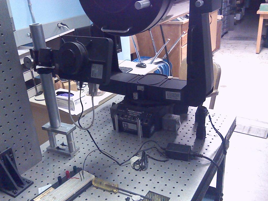 laying flat and the other affixed on the edge. The telescope is positioned at one end of the flat breadboard and pointed out from the cart.