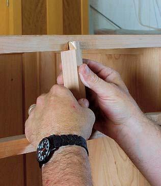 At the top of the opening, Brusso bullet catches hold the top of the doors in place. I insert the part containing the spring-loaded ball into the cabinet frame, and the catch into the top of the door.
