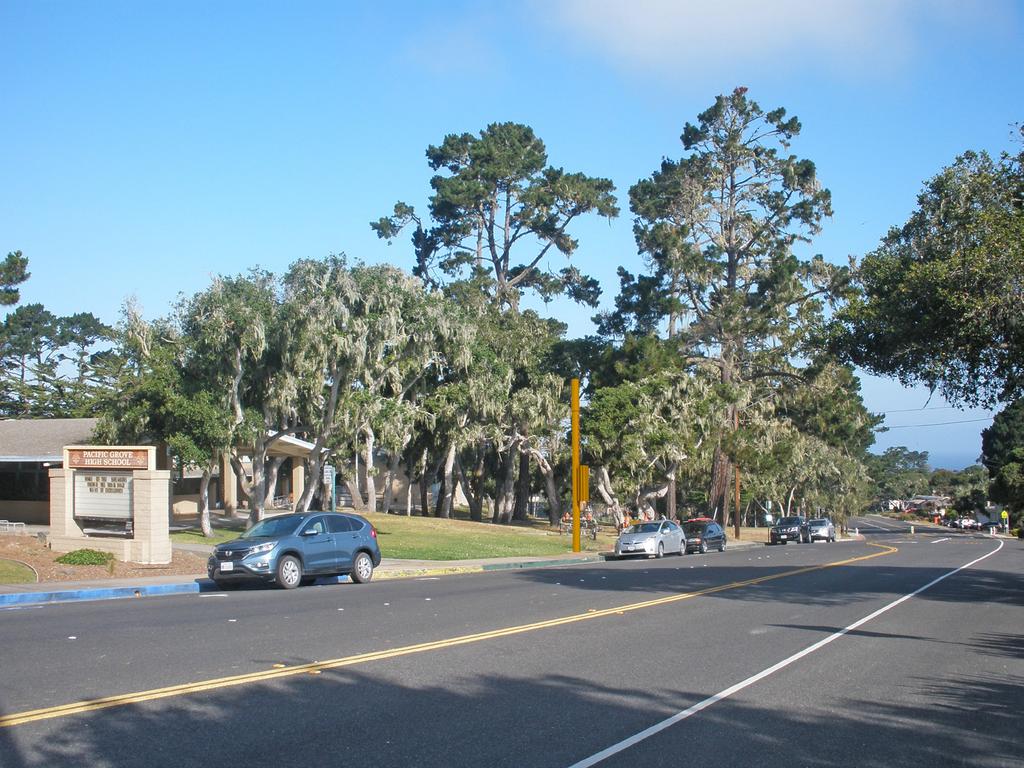 ATTACHMENT H - Rendering Design Option C Yellow Paint Pacific Grove HS SC1 ROW in front of 615 Sunset Drive Pacific Grove CA 93950 View 2 proposed pole with antenna and pole mounted equipment cabinet