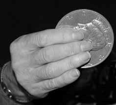 ) Hold the coin between the thumb and the first and second fingers.