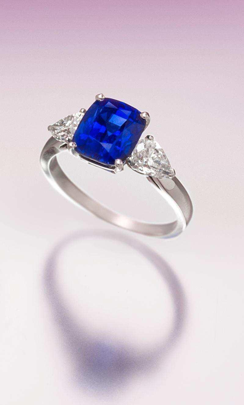 Lot 471 A Fine Platinum, Sapphire and Diamond Ring, containing one cushion cut sapphire weighing approximately 3.36 carats and two pear shape diamonds weighing approximately 0.83 carat total.